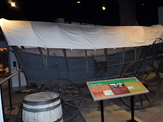 a covered wagon and wooden barrels on display at the Durham Museum in Omaha, Nebraska