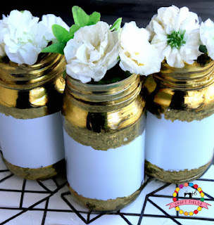 Painted Mason Jars: These mason jars have been painted with a metallic gold paint and adorned with white flowers.