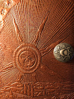 Leather book cover embossed with a mediaeval sun design. A round pewter knob shows a crescent moon in an eight-rayed corona.
