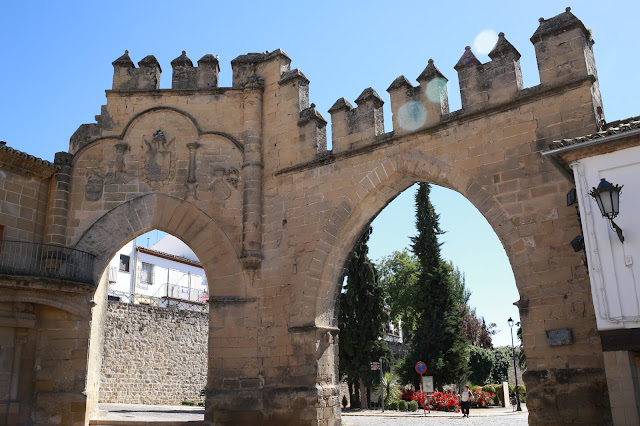 Dos arcos medievales con almenas que salen de una plaza.