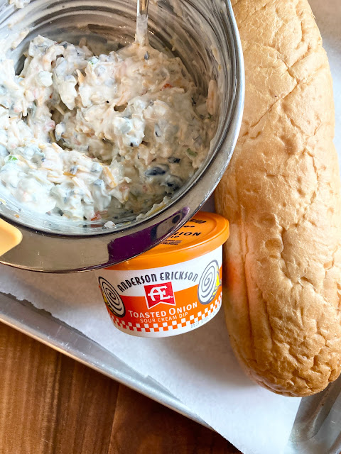A mixing bowl of the dip next to a loaf of French Bread and AE Dairy dip.
