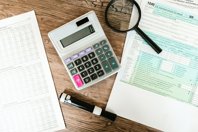 A gray calculator and a black magnifying glass on a brown wooden surface, isolated and in focus.