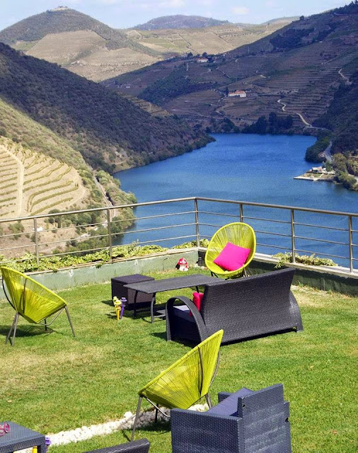 Panorâmia o vale do Douro e algumas mesas e cadeiras num jardim