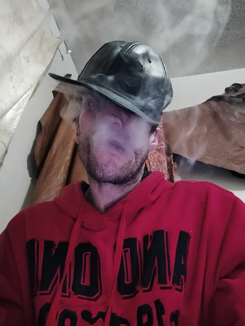 C 7/7 OLB blowing smoke sideways to left of face hat pointed sideways