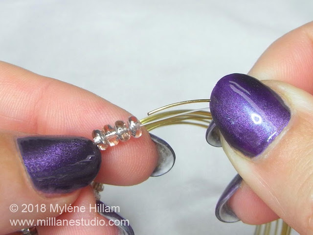 Transferring the Apollo Gold Czech glass rondelles onto the memory wire from the bead strand