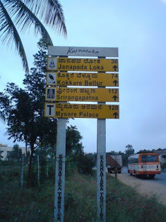 Road sign listing distances to prominent tourist attractions on Mysore Road 