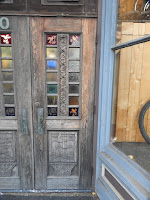 Old wooden door with glass panels and a carved wooden baseboard.