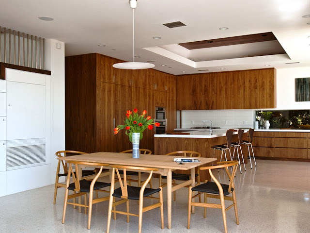 Picture of wooden dining table and chairs in the dining room and dark brown furniture in the kitchen with kitchen island