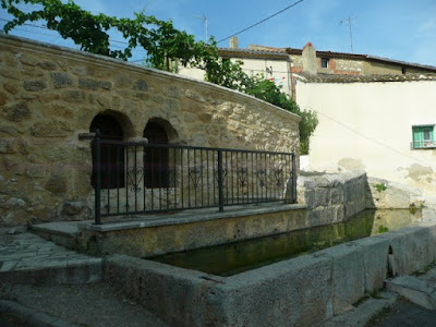 arcos de la fuente, barandilla y pilón. Por encima de la fuente se ven parras