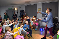 Zdjęcie przedstawia magika Piotra Szumnego podczas pokazu iluzjonistycznego.