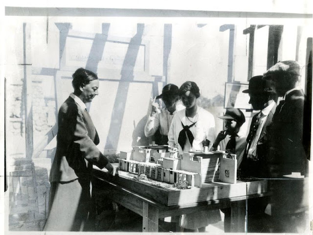 Alice Constance Austin showing model of house to Llano del Rio colonists, May 1, 1917. (Yale Collection of Western Americana, Beinecke Rare Book and Manuscript Library)