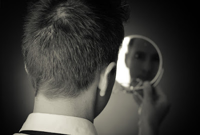 A man looks at his reflection in a mirror