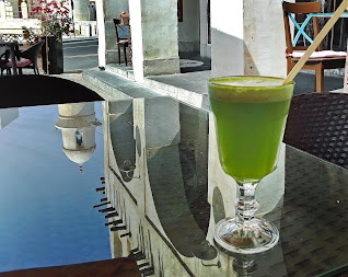 Green juice in glass on table reflecting Doha, Qatar