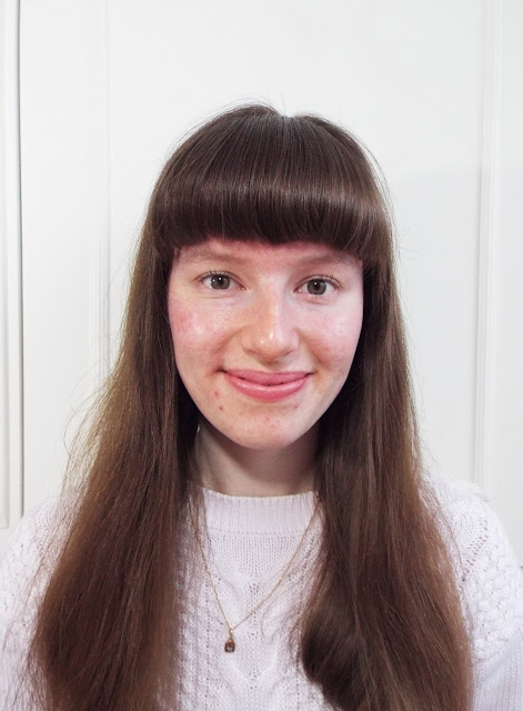 Ellie - blogger of Ellie Bows & Sparkles - with no makeup, full fringe and brown hair, curled lashes and pink lips, wearing a lilac jumper and her Nan's little gold necklace
