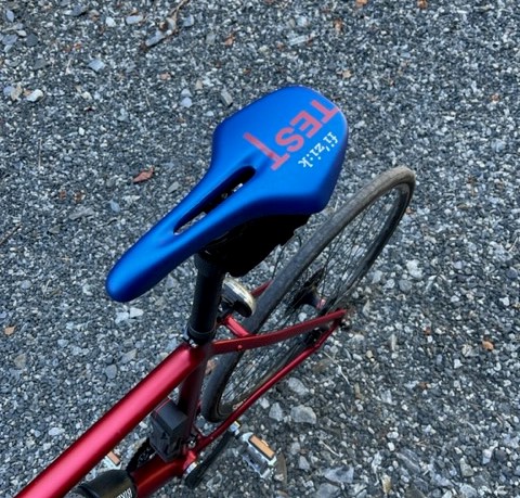 Blått sykkelsete på rød sykkel