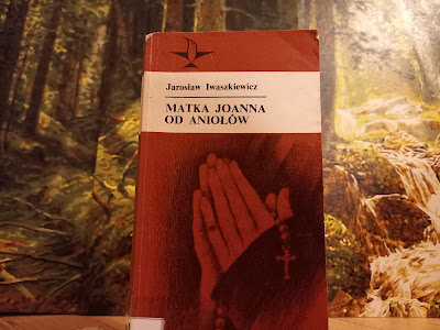 Książka na tle obrazu przedstawiającego las