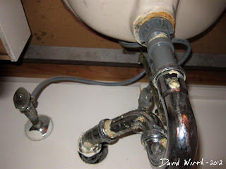 pipes and hoses under sink, below under sink drain, caulk, putty, shut off valve