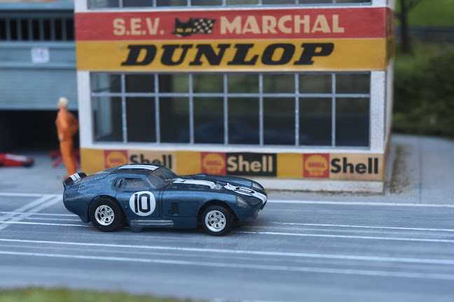 AFX Daytona in front of an industrial building with Dunlop and Shell advertisements