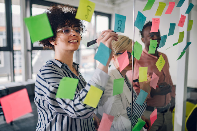 Team members brainstorming by writing and sharing ideas on sticky notes.