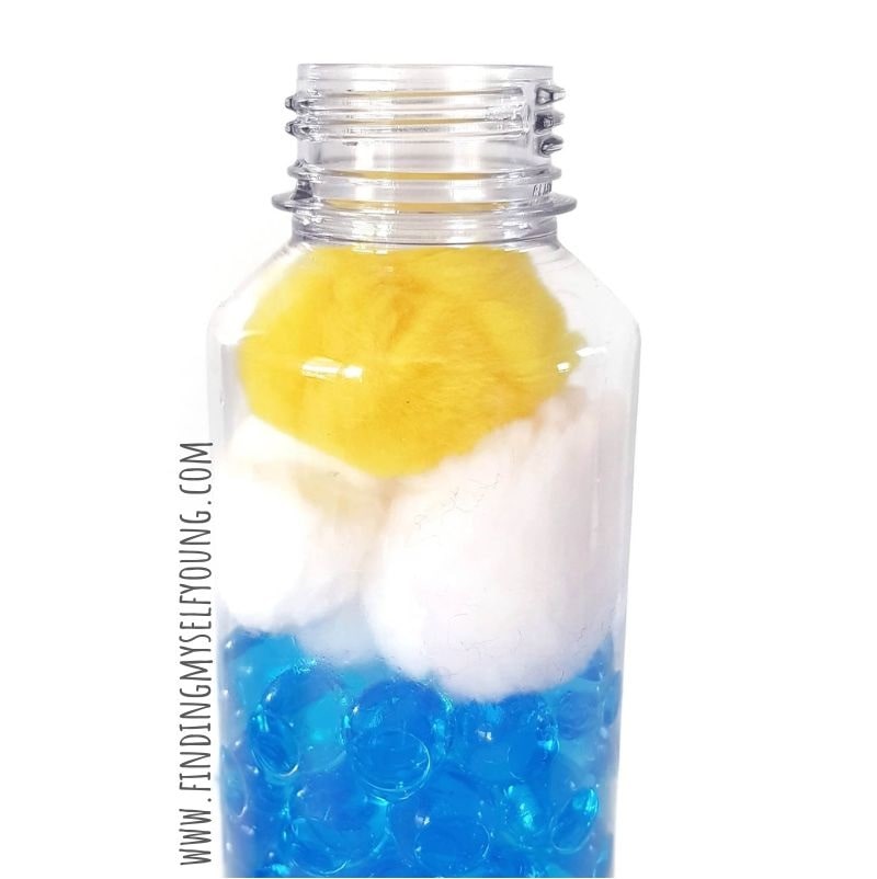 pom pom and cotton balls added to sensory bottle