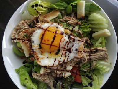 pulled pork in a salad with a sunny heritage egg, cheese topped with balsamic glaze