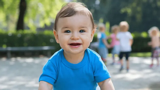 Menino bebê com uma camiseta azul em um parque pousando para foto Nomes de Meninos Com J