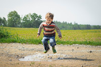 A little boy jumping over a sand pit