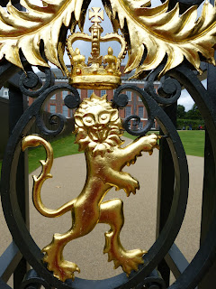 Close-up picture of a golden lion on a gate with an elegant building behind
