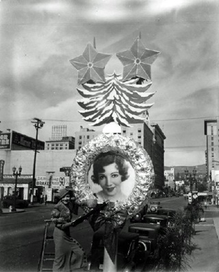 Claudette Colbert next to her image on a Christmas decoration near Hollywood and Vine.