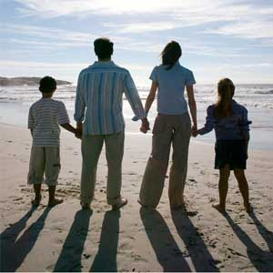 A family holding hands looking at the ocean.