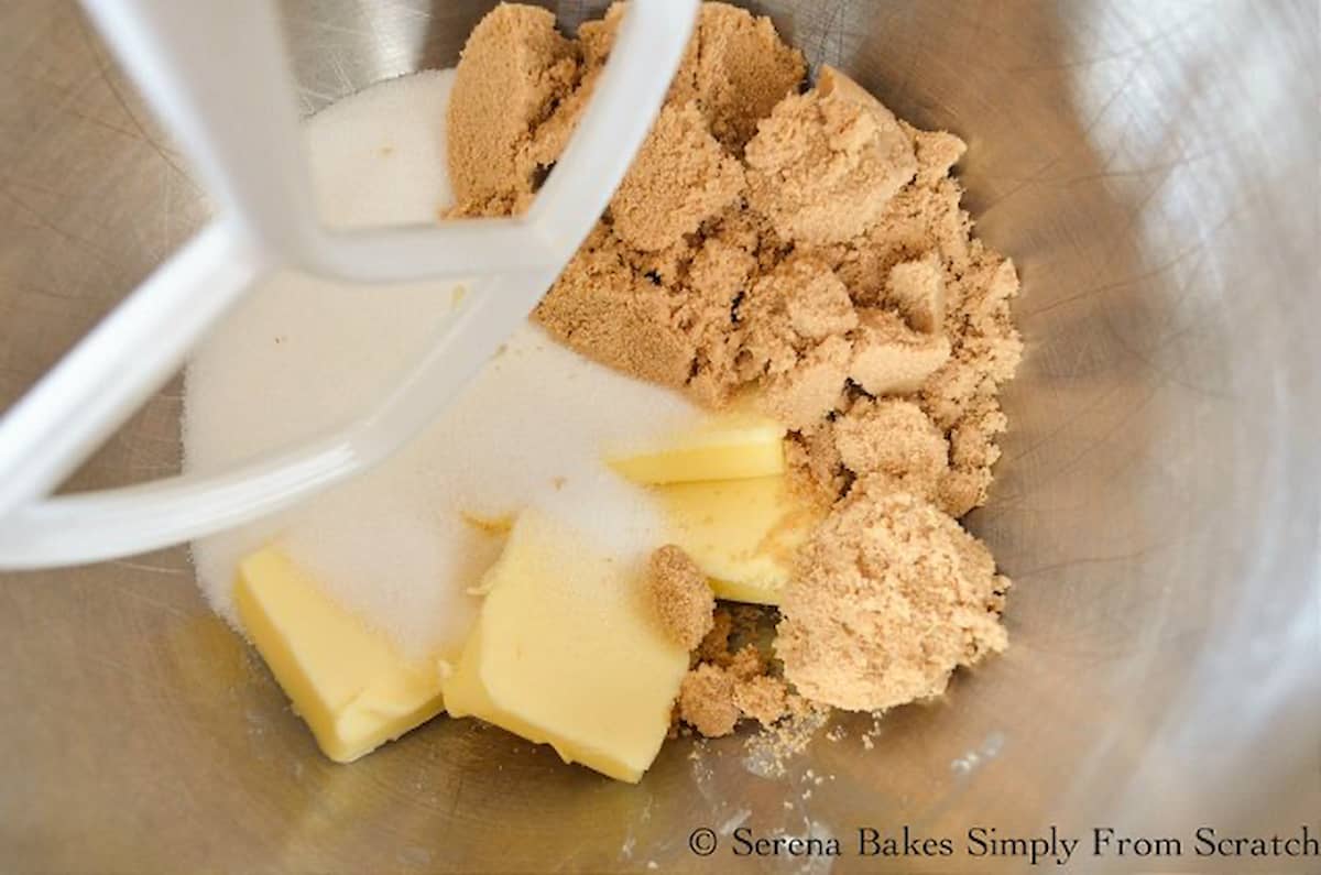 Butter, granulated sugar, and brown sugar in a stainless steel mixing bowl fitted with a paddle attachment.