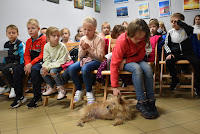 Zdjęcie przedstawia dzieci bawiące się z suczką Luną.