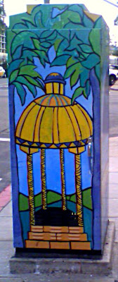 A utility box painted with a golden gazebo framed by palm trees.