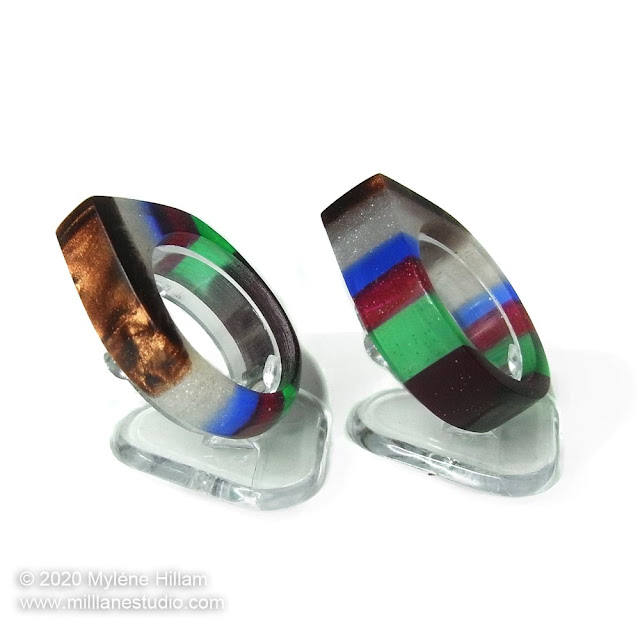 Two multicoloured striped resin rings viewed from the side to highlight the shimmering mica powder layers