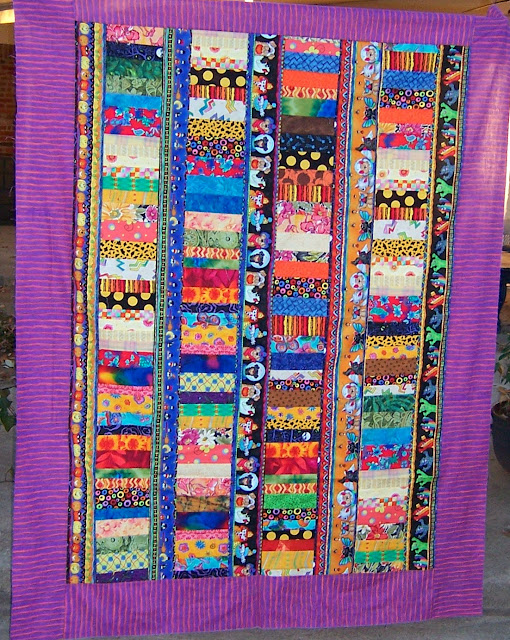 Striped Halloween fabric forms sashing between columns of colorful coins to create this happy quilt.