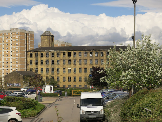 Pellon Lane Mill with blocks of flats behind and car-park in front.