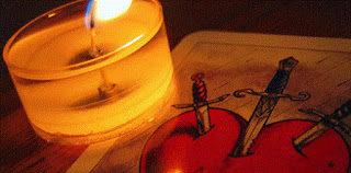 Imagen de una vela encendida encima de una baraja de espadas