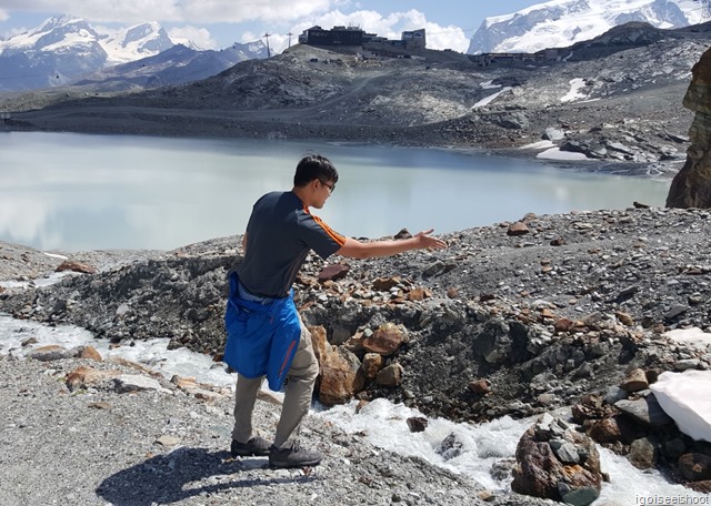 Playing with stones by the stream of glacier melt-water. Trockener Steg Station in the background.