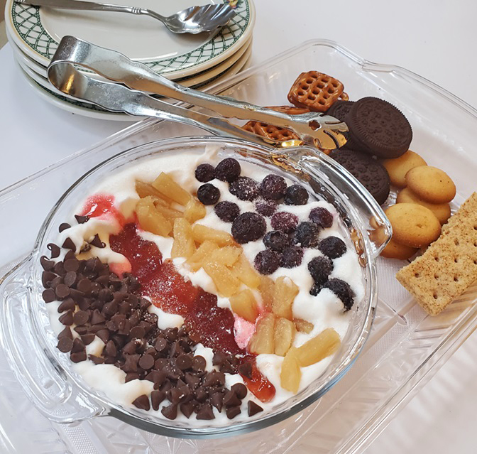 whipped cheesecake dip topped with several assorted toppings in rows for a dessert dip