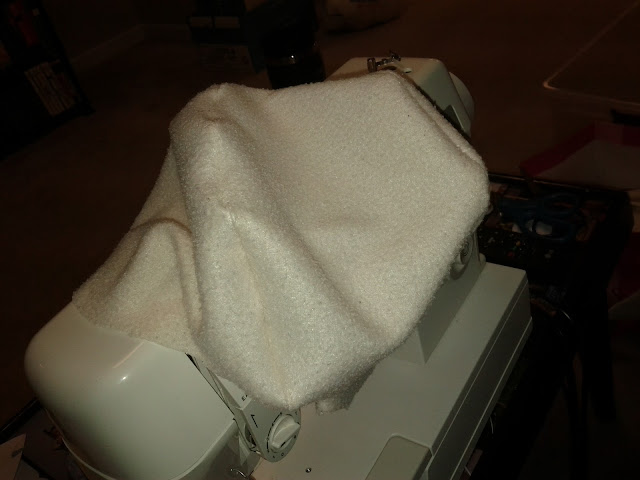 A large piece of white fleece is draped over an off white sewing machine.