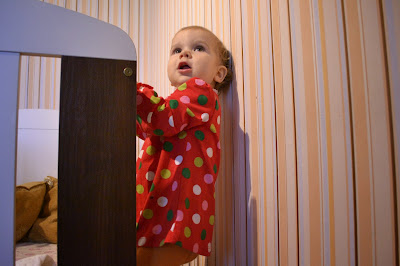 small girl in child's room behind the cradle