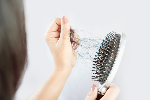 Hand of a girl removing her broken hair from a hair brush