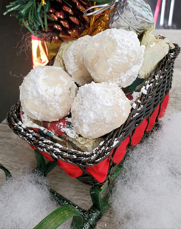 this is a Christmas sleigh full of butter cookies covered in powdered sugar that look like snowballs