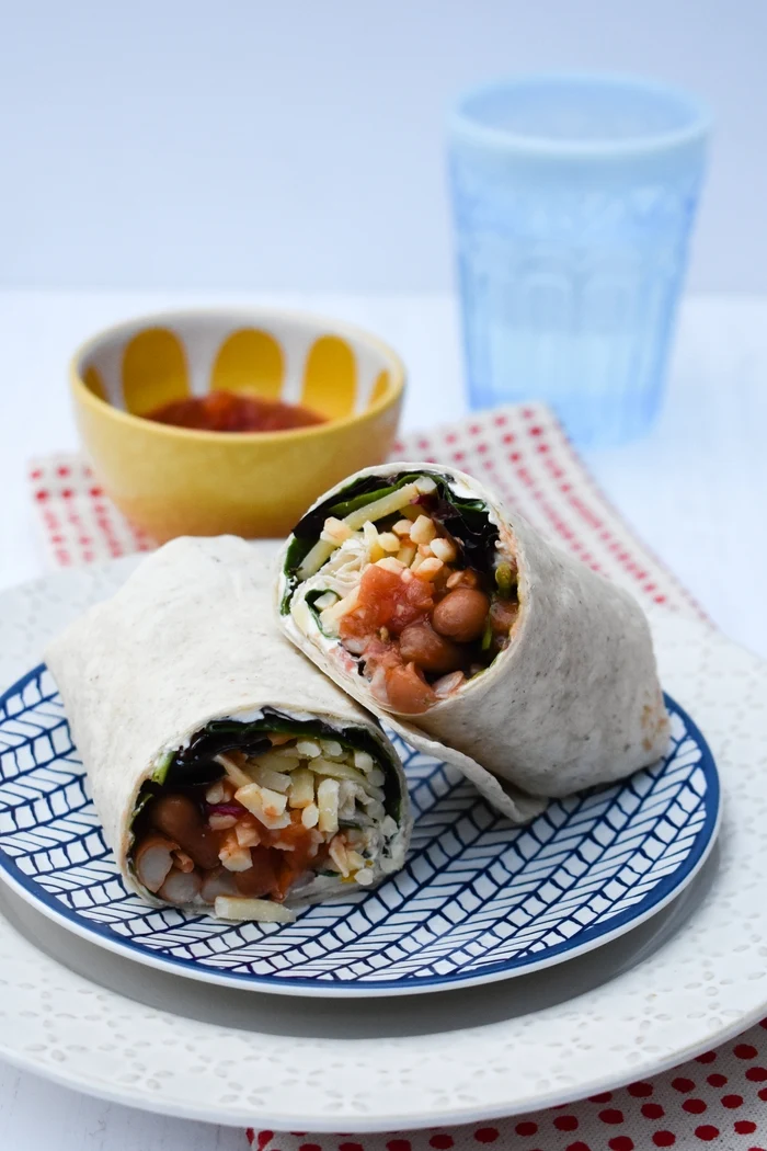 a Spicy Bean Lunch Wrap on a spotty napkin with a bowl of salsa