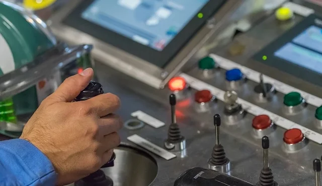 A man is controling a machine from control room for automation.