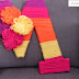 Monogramma e pacchetto decorati con lana-viola-fucsia-arancio-giallo