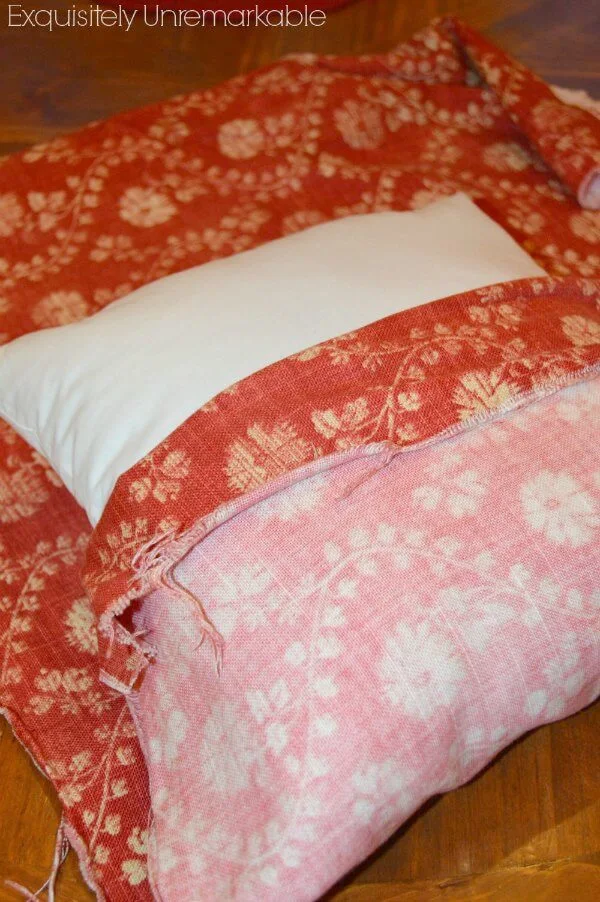 red fabric folded over white square pillow form
