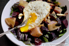Image of a bowl of chopped bok choy topped with roasted potatoes & beets and a fried egg with runny yolk