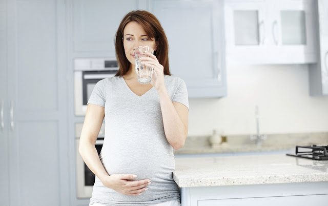 A pregnant woman is drinking water