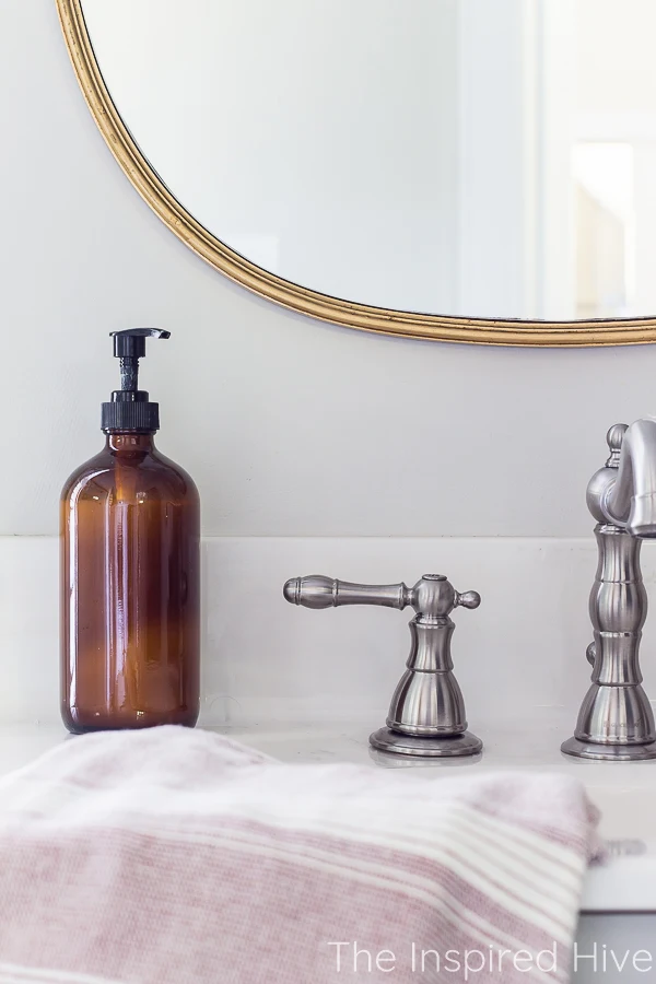 Gold mirror, nickel faucet, amber glass soap dispenser